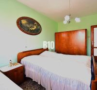A bedroom in a family house with solid wood furniture and a decorative painting on the wall.