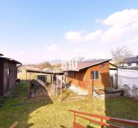 A garden at a family house in Žilina with a wooden extension and a view of the countryside.