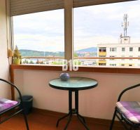 A balcony with a view of Žilina from a 4-room apartment, two chairs, a table.