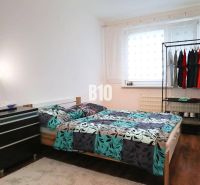 Bright bedroom in a 4-room apartment with a bed and wood-patterned flooring.