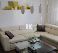 Elegant living room in a 4-room apartment with a cream sofa and wooden decor flooring.