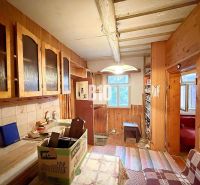 A family house kitchen with wooden cabinets and a tiled wall.