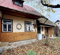 A family house in Kotešová with old wooden cladding and falling leaves in the garden.