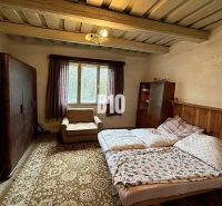 A bedroom in a family house with a carpet, sofa, and bed under a wooden ceiling.