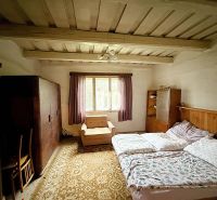 A bedroom in a family house with a wooden ceiling, a bed, and furniture.