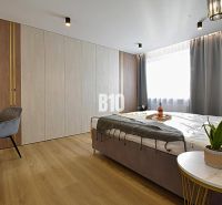 A bedroom with a desk, bed, and floor with a wooden decor in a 3-room apartment.