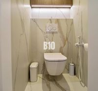 A toilet with marble tiles in a 3-room apartment, includes a wall-hung bowl and a bidet.