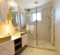 A bathroom in a 3-room apartment with marble tiles, two sinks, and a shower.