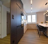 A kitchen in a 3-room apartment with a dining table and a floor with a wood decor.