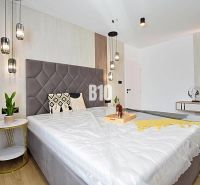 Bedroom in a 3-room apartment with a large bed, hanging lamps, and a wooden decor floor.