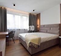 A bedroom in a 3-room apartment with a wood-patterned floor and stylish seating.