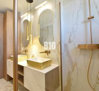 Luxury bathroom with marble tiles and gold accessories in a 3-room apartment.