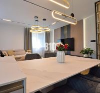 Living room in a 3-room apartment with wood-patterned flooring, a couch, and interesting lighting.