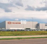 Kia Motors building in Žilina, commercial land with parked cars and grassy area.