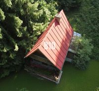 A cabin in Kunerad with a sloped roof and surrounded by dense tree vegetation.