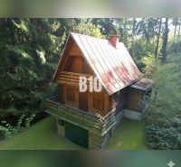 A cottage in Kunerad surrounded by forest with wooden elements and a stone foundation.