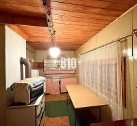 A kitchen in a cabin with a wooden ceiling and an antique stove, complemented by a curtain.