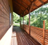 A wooden terrace of a cottage in Bytča surrounded by greenery and forest scenery.