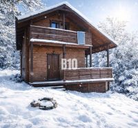A snowy wooden cabin in Bytča surrounded by forests.
