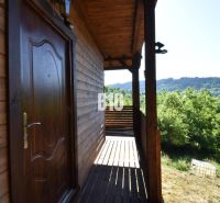 A cottage near Bytča with a wooden terrace surrounded by green nature and forests.
