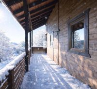 A snowy terrace of a wooden cabin in Bytča with a view of the winter landscape.