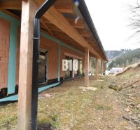 A family house under construction with a wooden shelter, flat terrain, and surrounding landscape.