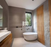 A bathroom in a cabin with a freestanding bathtub, wooden details, and a large window.