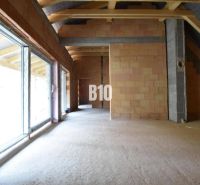 Unfinished interior of a family house with large windows and brick walls.