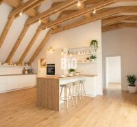 A kitchen in a cottage with a wood-patterned floor, wooden beams, and houseplants.