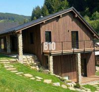A wooden cottage in Horná Mariková surrounded by greenery and hilly landscape.