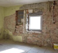 A room in a family house with brick walls and a bucket on the floor.
