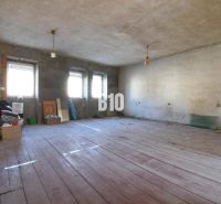 A spacious room in a family house with wooden flooring and unfinished walls.