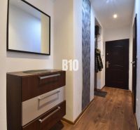 A hallway with a mirror, a chest of drawers, and a wooden decor floor in a 3-room apartment.