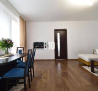 Living room in a 3-room apartment with wooden decor and a dining table.