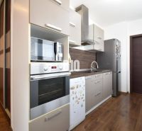 A kitchen in a 3-room apartment with a wooden decor floor and modern equipment.