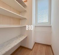A small room in a vacation apartment with shelves and a window, floor with wood decor.