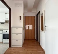 A hallway with a wooden decor floor in a Holiday Apartment, with a kitchen in the background.