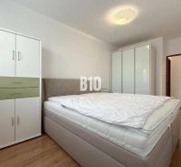 A bright room in a holiday apartment with a bed, wardrobes, and a wooden decor floor.