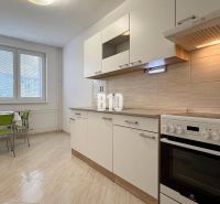 Bright kitchen in a Holiday Apartment with a stove and a table with green chairs.