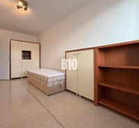 A bright room in a holiday apartment with a bed, wardrobe, and shelving unit.