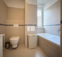 Bathroom in a holiday apartment with a bathtub, toilet, and modern tiles.