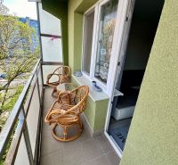 Balcony with two rattan chairs and a table, view of greenery, 3-room apartment.