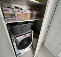 Storage space in a 3-room apartment with a washing machine and shelves.