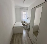 A simple room with a bed, a wardrobe, and a desk, with a wooden-patterned floor.