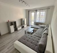 Living room in a 3-room apartment with a wooden decor floor, a large sofa, and a television.