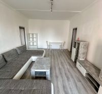 Living room with wood-patterned flooring and a gray sofa in a three-room apartment.