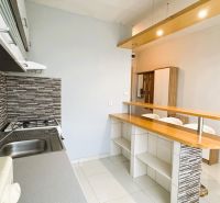 A kitchen in a studio apartment with a bar counter and a wooden decor floor.