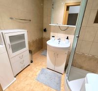 A bathroom with a bathtub, sink, and storage cabinets in a studio apartment.