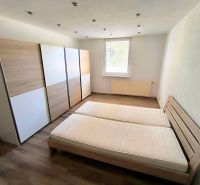 Bedroom with a large wardrobe, double bed, and wooden decor flooring in a studio apartment.