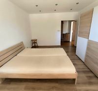 A bedroom in a studio apartment with a bed and a wooden decor floor.